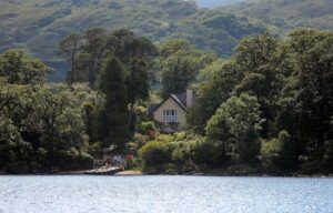 Dinis Cottage behind some bushes viewed from Lough Leane